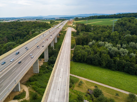 Aerial view of a German Autobahn with construction works for a new railway bridge next to it. Drone photo taken at Denkendorf near Stuttgart - on a weekend, hence not much truck traffic.