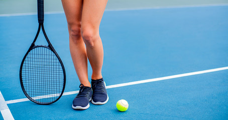 Beautiful woman legs with tennis racket on tennis court