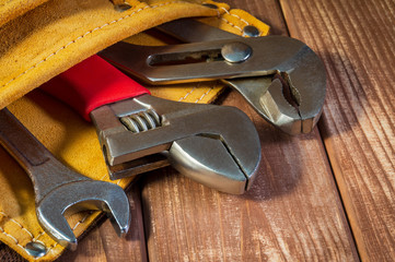 Tools and instruments in leather bag isolated on wooden background.