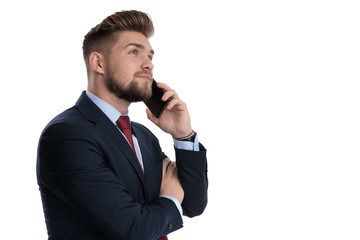 Hopeful businessman talking on his phone and looking up