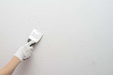 Working tool, spatula in hand against the background of a white wall, work plasterer. Putty walls...
