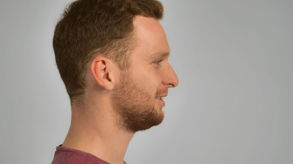 Obraz premium half-face young man with red hair and beard smiling. happy guy with cheerful smile