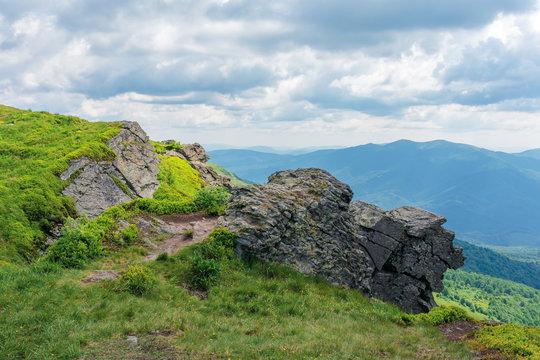 rock on the edge of a hill. beautiful summer scenery in mountains. grass on the slope beneath a cloudy sky