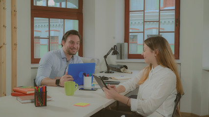 Partners celebrating good news. Happy businessman looking on screen computer reading mail. Attractive young woman rejoice about new deal.