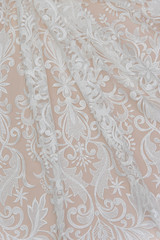 a background image of ivory-colored lace cloth. White lace on beige background.