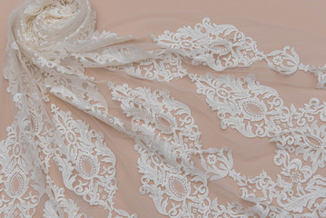 a background image of ivory-colored lace cloth. White lace on beige background.