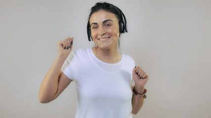 Adult caucasian woman with black hair listening music using headphone dancing with smile. Portrait...