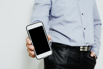 Phone in hand with a blank screen. A man dressed in a business shirt holds in his hand a phone with a blank display. Content completion concept.