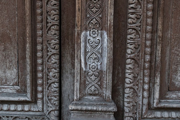 Fototapeta na wymiar Ornamental carving wooden surface closeup of ancient door of Louvre museum in Paris France. Ornate wood texture of old double door closeup. Weathered wooden patterns of doorway panels.