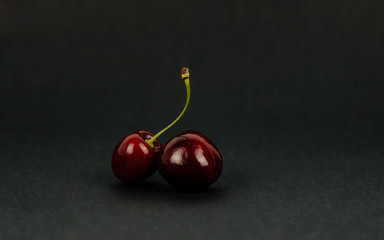 Sweet cherries on a dark, black background. The concept of eating fruits, eating cherries. Red cherries, insulated cherries. A balanced diet, providing vitamins.