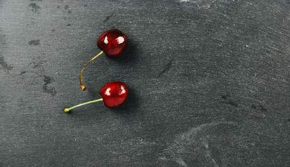Sweet cherries on a dark, black background. The concept of eating fruits, eating cherries. Red cherries, insulated cherries. A balanced diet, providing vitamins.