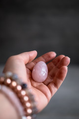 Woman holding in hand a vaginal (yoni) egg. Rose quartz crystal egg. Copyspace