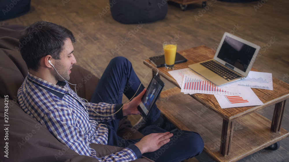 Aufkleber manager headphones to communicate with clients using the tablet on the table is a laptop and documen