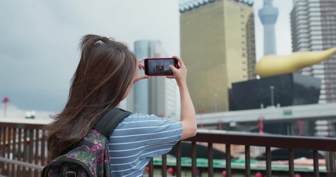 Woman travel to tokyo, take photo on cellphone in the city