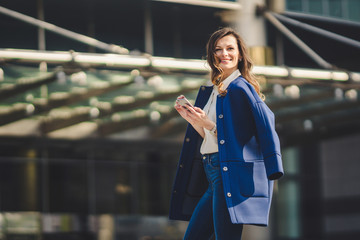 Office buildings city people in suit. Caucasian businesswoman using smartphone with hand. Business concept. Portrait stylish business woman in fashionable clothes holding Phone near office building