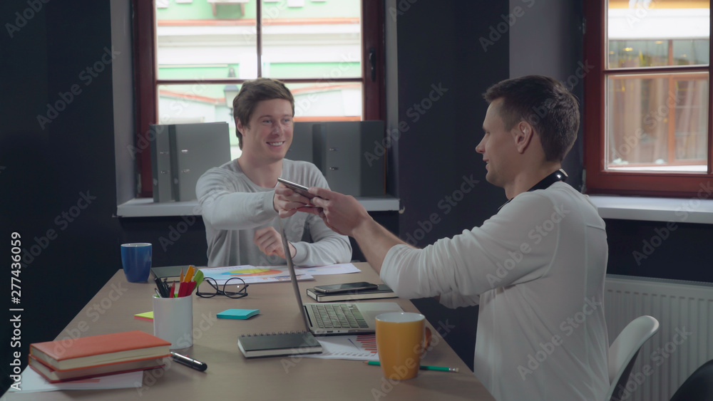 Aufkleber happy colleagues using modern gadgets in the meeting. young professional business men sitting at the