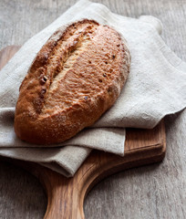 Loaf of whole wheat bread wooden board on kitchen table