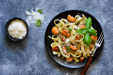 Pasta with cream sauce, mussels and parmesan on a concrete background.