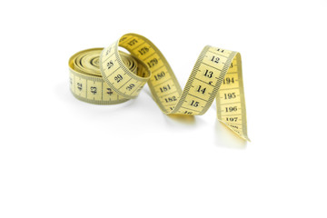 The yellow measuring centimetric tape curtailed by a spiral on a white background. Sewing accessories