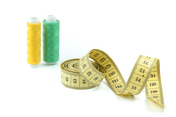Set of sewing accessories: The yellow measuring centimetric tape curtailed by a spiral on a white...