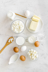 Fototapeta na wymiar Fresh dairy products for breakfast with milk, cottage, eggs, butter, yougurt on white marble background top view mock up