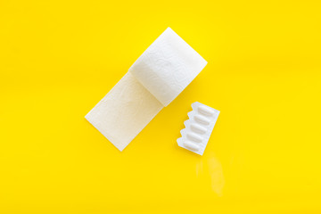 Toilet paper roll and rectal suppository for proctology diseases concept on yellow background top...