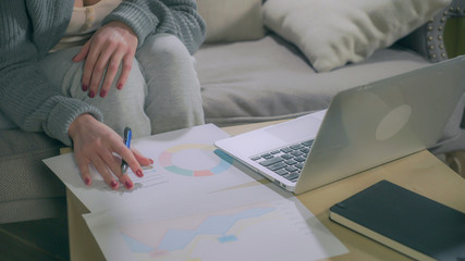 Female hands make notes in charts and laptop. Static