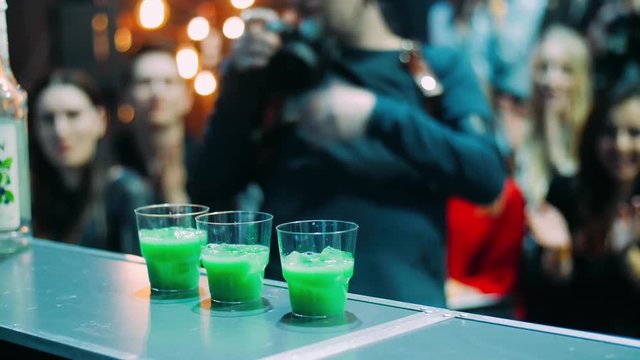Bartender masterly making three green cocktails at same time at nightclub
