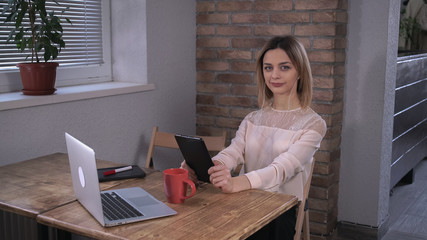 Attractive woman making a video call by tablet in the office during the coffee break.