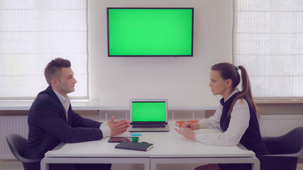 manager tell about new services customer. Business woman with long blond wear explain some details adult man. Employees talking in boardroom. Coworkers sitting at working place in room with white