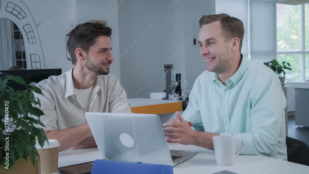 Poster young professional colleagues discussing their work. man looking at a computer screen. men working i