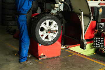 Man worker employee with wheel balancing machine for car tire repair service.