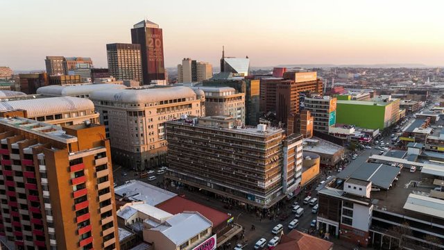 Loop of Medium timelapse at sunset/nightfall showing the view across New Town. Jeppes town and the city centre of Johannesburg during peak traffic with the hustle and bustle of people in the streets, buildings and taxis, South Africa