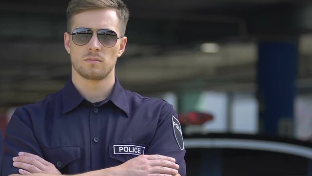 Portrait of policeman in sunglasses providing public safety and security in city