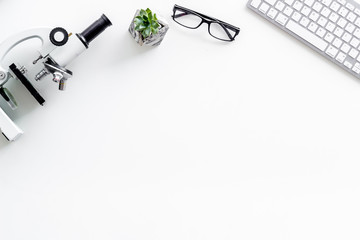 Medical research with microscope, keyboard, glasses on white background top view space for text