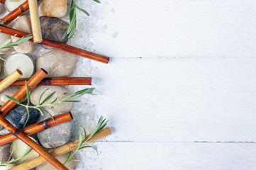 SPA flat lay composition. Sea pebbles, bamboo shoots, scented candles, sea salt on a light wooden background. Top view