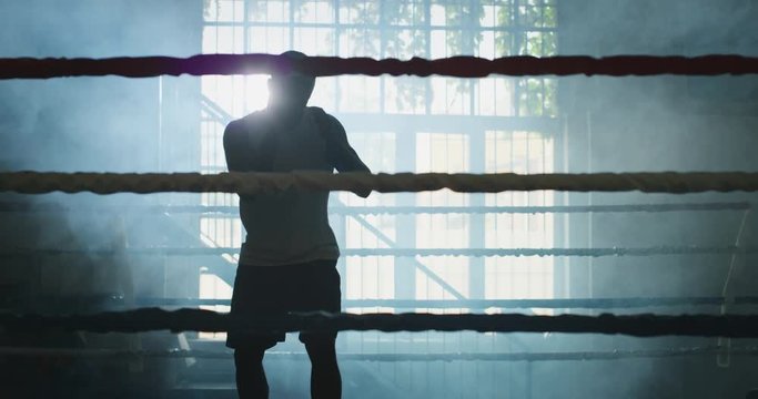 Cinematic slow motion shot of a professional young muscular african man is practicing shadow boxing work out in a ring. 