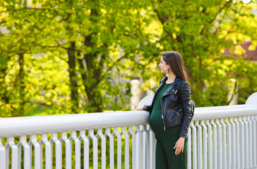 pregnant girl on the bridge. Portrait of a young happy pregnant woman on a white bridge. Rest and enjoy nature - obrazy, fototapety, plakaty