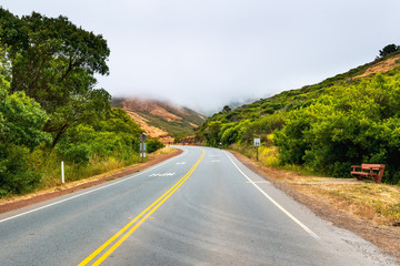 Paved road with a 35 mph speed limit going through Marin Headlands; cloudy and foggy day; Marin...
