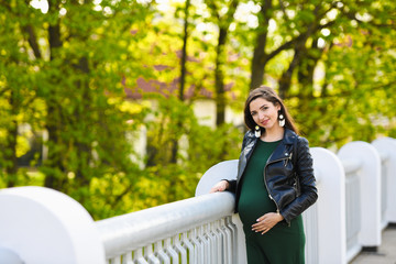 pregnant girl on the bridge. Portrait of a young happy pregnant woman on a white bridge. Rest and enjoy nature - obrazy, fototapety, plakaty