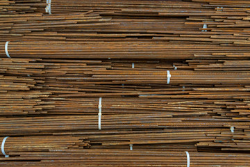 Top view close up stack of straight old rusty high yield stress mild reinforcement steel or iron bars bundle. Background horizontal random pattern from bunch of mild steel bars. 