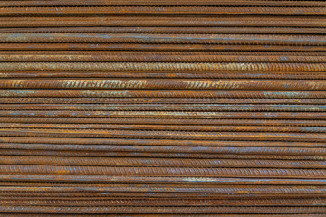 Top view stack of straight old rusty high yield stress deformed reinforcement steel or iron bars. Background horizontal random pattern of deformed iron bars. 