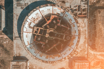 Aerial top view of abandoned and ruined Nuclear Power Plant, round tower of atomic reactor in sunlight, drone shot