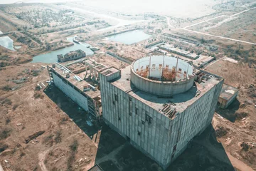Fototapeten Verlassene Gebäude Aerial view of abandoned and ruined Nuclear Power Plant or station, round tower of atomic reactor, large industrial demolished building  © DedMityay