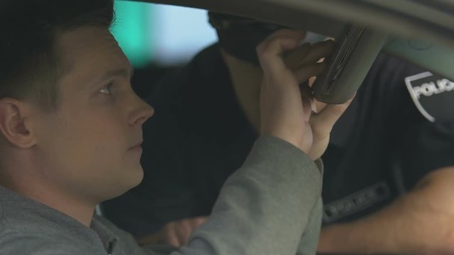 Police officer checking car documents of nervous driver, smuggling suspicion