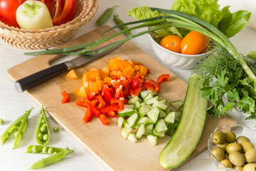 Obraz na płótnie Canvas Cooking cutting vegetables on salad on cutting board. Healthy vegan food concept