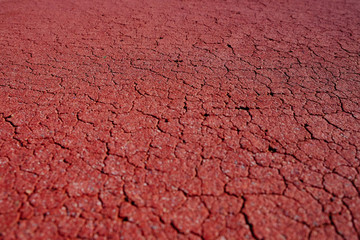 Red cracked surface of an old playing field, selective view perspective.