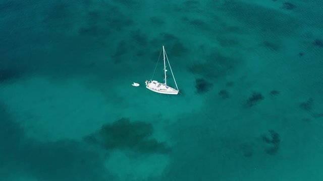 View from above, stunning aerial view of a sailing boat floating on a beautiful turquoise clear sea. Maddalena Archipelago National Park, Sardinia, Italy.
