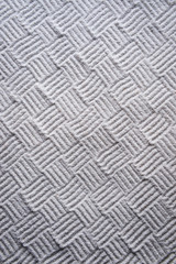 Woven cross-hatch pattern hand-raked into an abstract textured background in the monochrome white sand gravel of a Japanese Zen garden