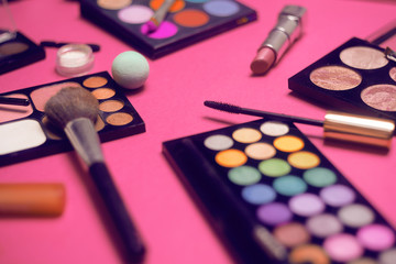 Cream, lipstick, powder, mascara and brushes. Shadows for a make-up, sponges, gloss. Women's cosmetics on a bright background. Sales, discount cosmetics. Top view on pink background.